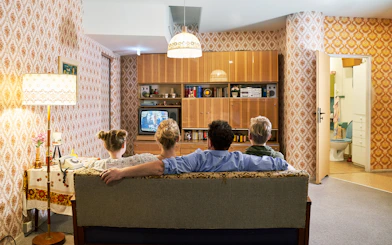 Family watching TV in a 1970s-style living room at DDR Museum German Apartment.