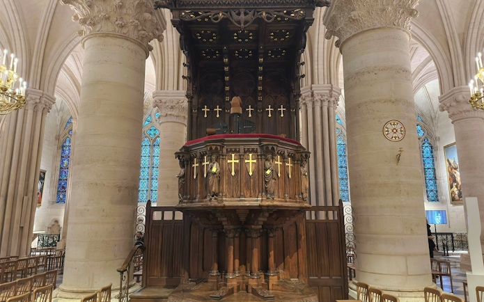 Pulpit with ornate carvings and stained glass windows inside Notre Dame Cathedral, Paris.