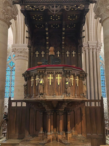Pulpit with ornate carvings and stained glass windows inside Notre Dame Cathedral, Paris.