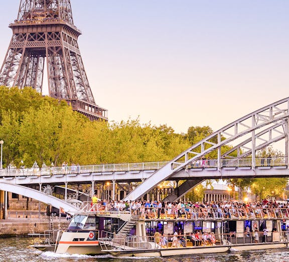 Seine River cruise boat near Eiffel Tower and bridge in Paris.