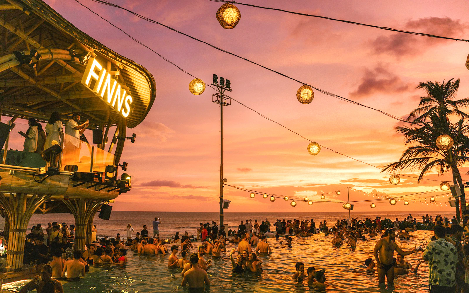 Crowd enjoying sunset at FINNS Beach Club Bali pool party.