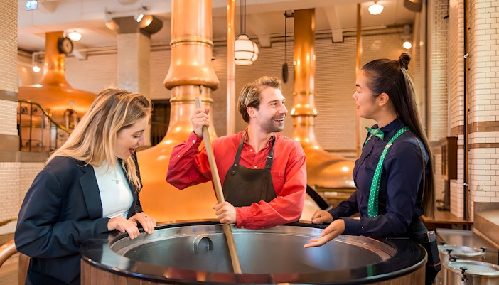 Guests with guide at brewing vat in Heineken Experience, Amsterdam.