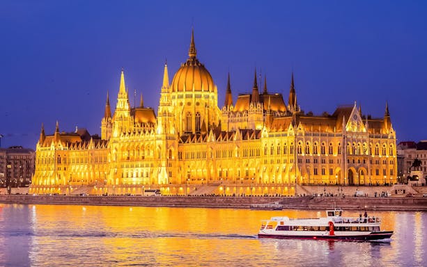 Budapest Danube River nighttime cruise with illuminated cityscape and historic buildings.