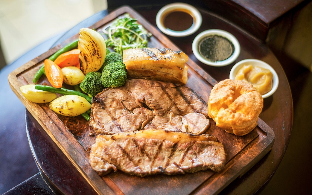 Traditional English Sunday roast with beef, Yorkshire pudding, vegetables, and gravy in a restaurant.