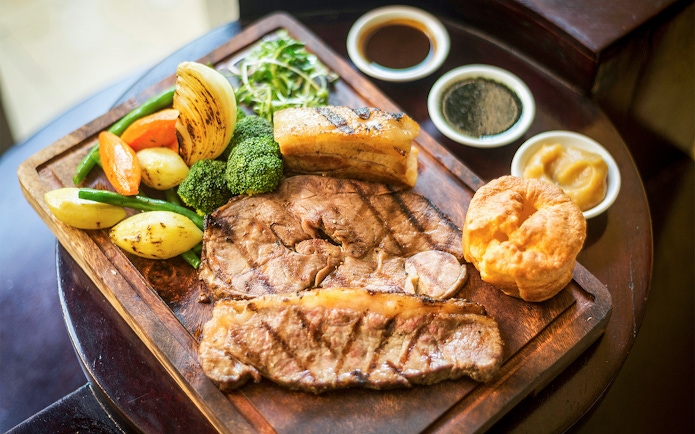 Traditional English Sunday roast with beef, Yorkshire pudding, vegetables, and gravy in a restaurant.