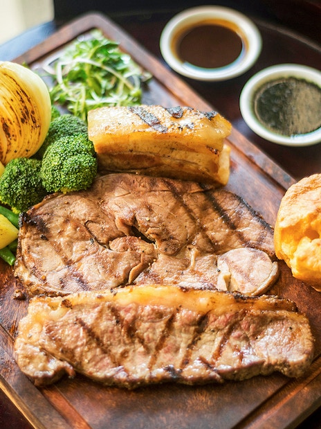 Traditional English Sunday roast with beef, Yorkshire pudding, vegetables, and gravy in a restaurant.