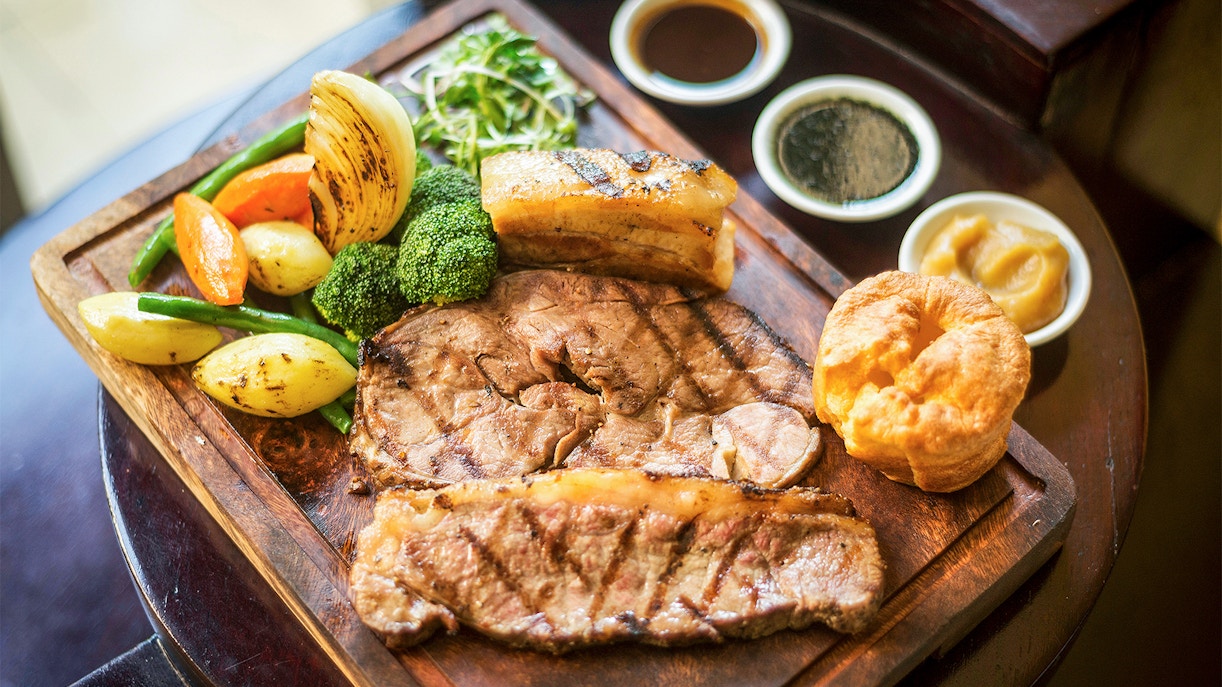 Traditional English Sunday roast with beef, Yorkshire pudding, vegetables, and gravy in a restaurant.