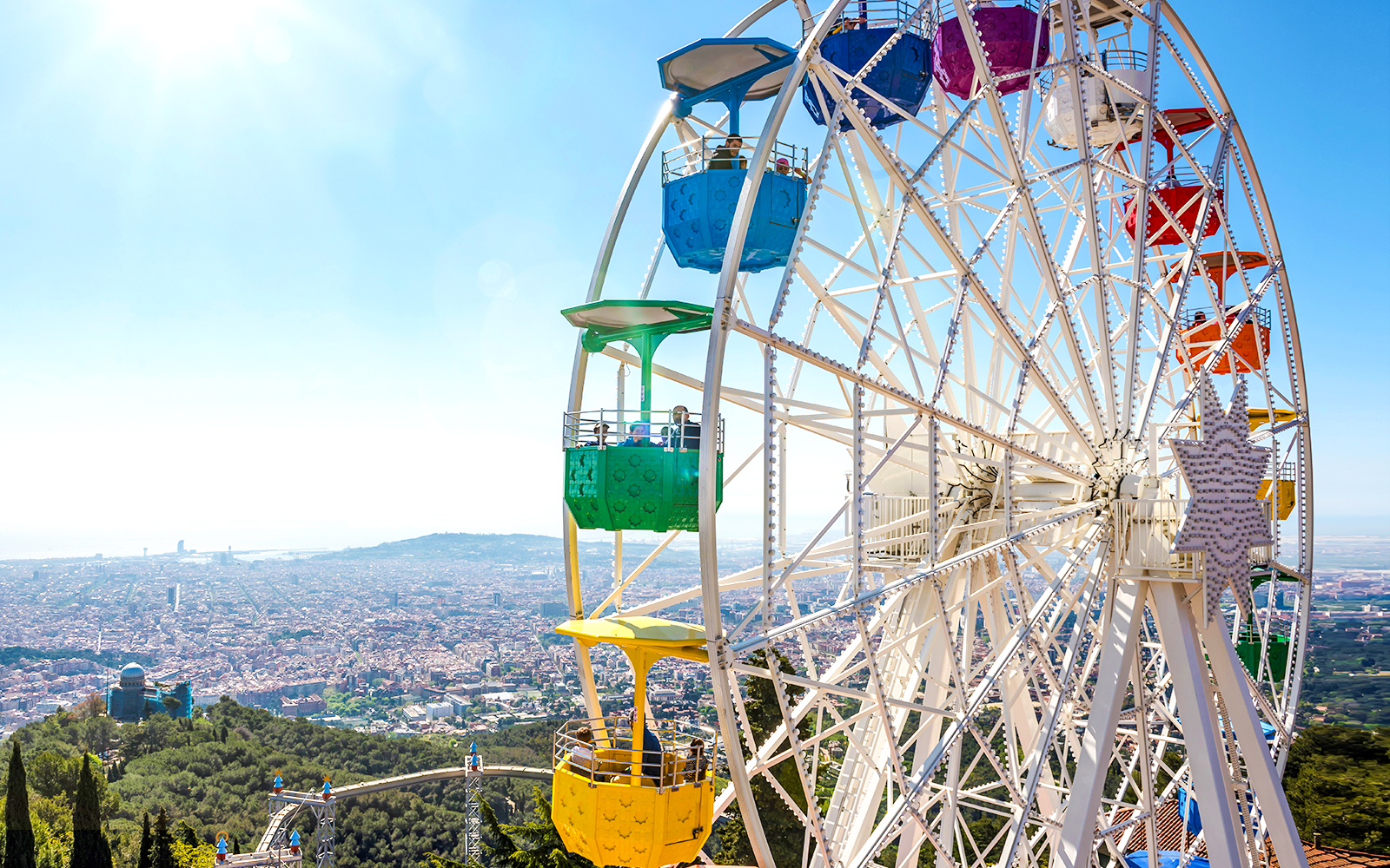 Ferris wheel at Tibidabo Amusement Park overlooking Barcelona cityscape.