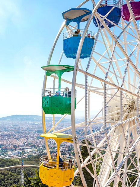 Ferris wheel at Tibidabo Amusement Park overlooking Barcelona cityscape.