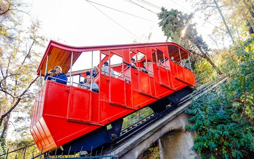 Santiago cable car ascending hillside with passengers.