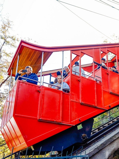 Santiago cable car ascending hillside with passengers.