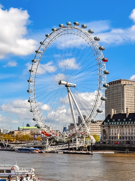 London Eye on the Thames River with cityscape background.