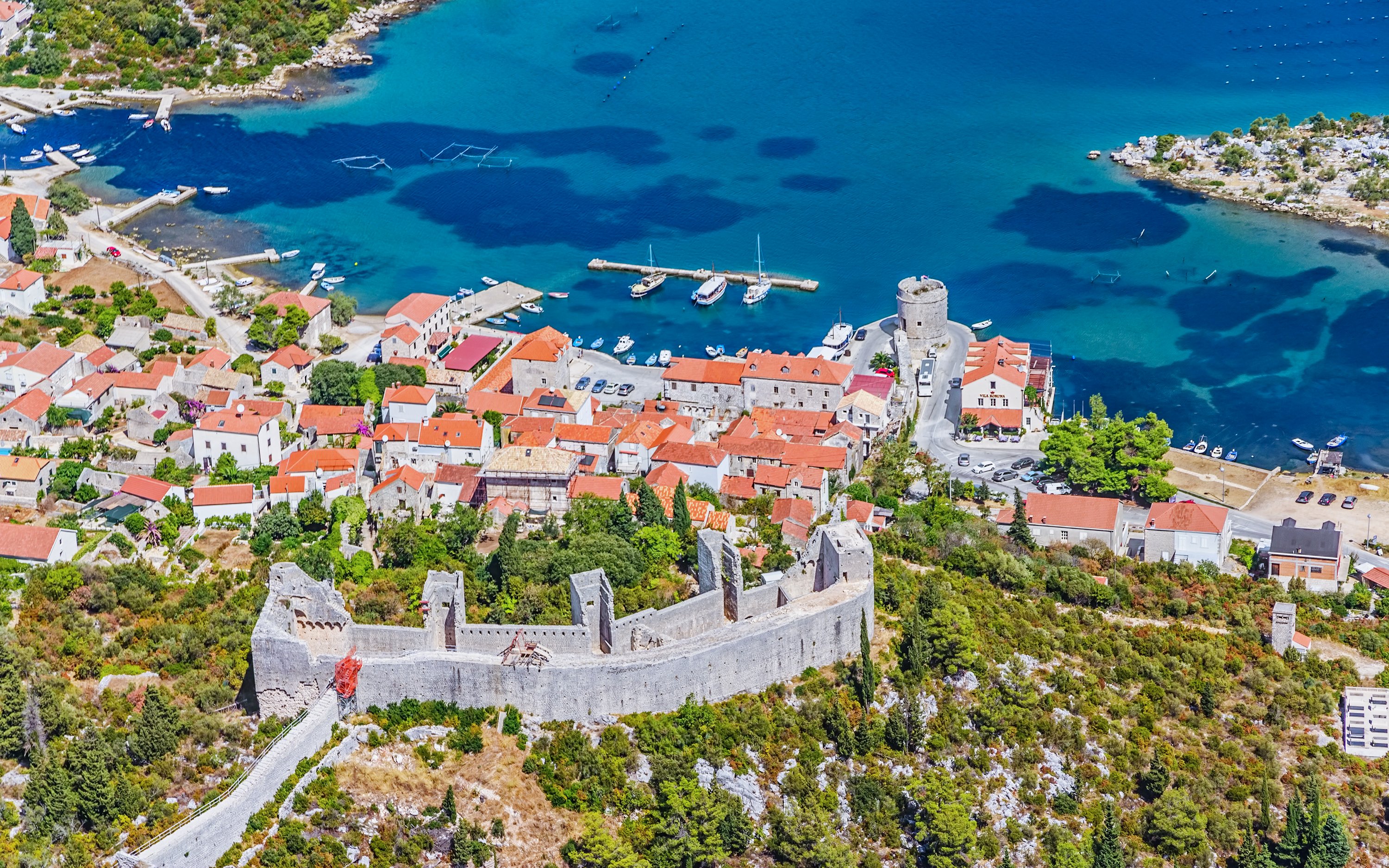Aerial view of Ston, Croatia, featuring historic walls and red-roofed buildings by the Adriatic Sea.