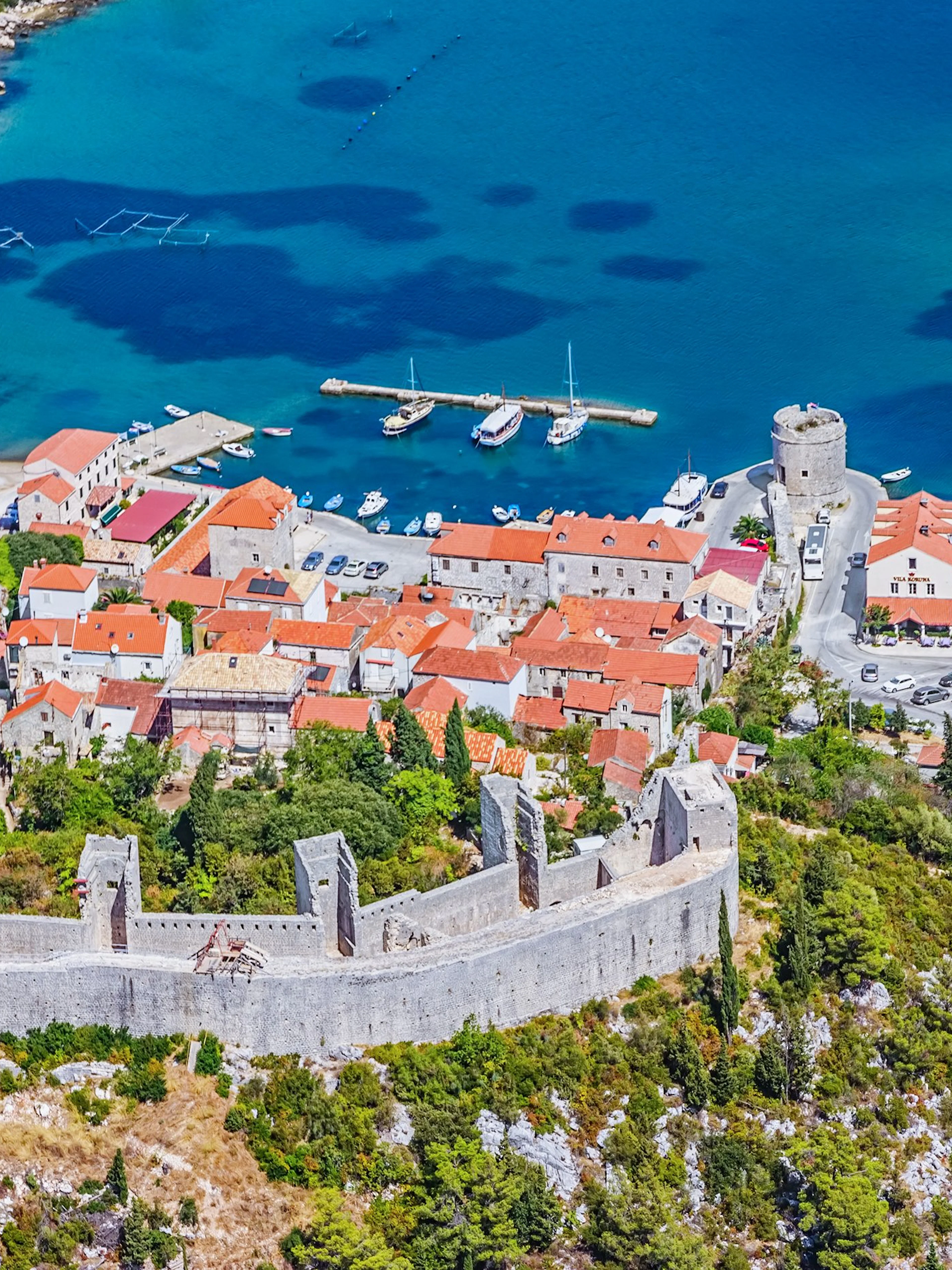 Aerial view of Ston, Croatia, featuring historic walls and red-roofed buildings by the Adriatic Sea.