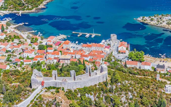 Aerial view of Ston, Croatia, featuring historic walls and red-roofed buildings by the Adriatic Sea.