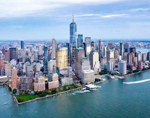 NYC skyline view from Westchester with iconic skyscrapers and Hudson River in the foreground.