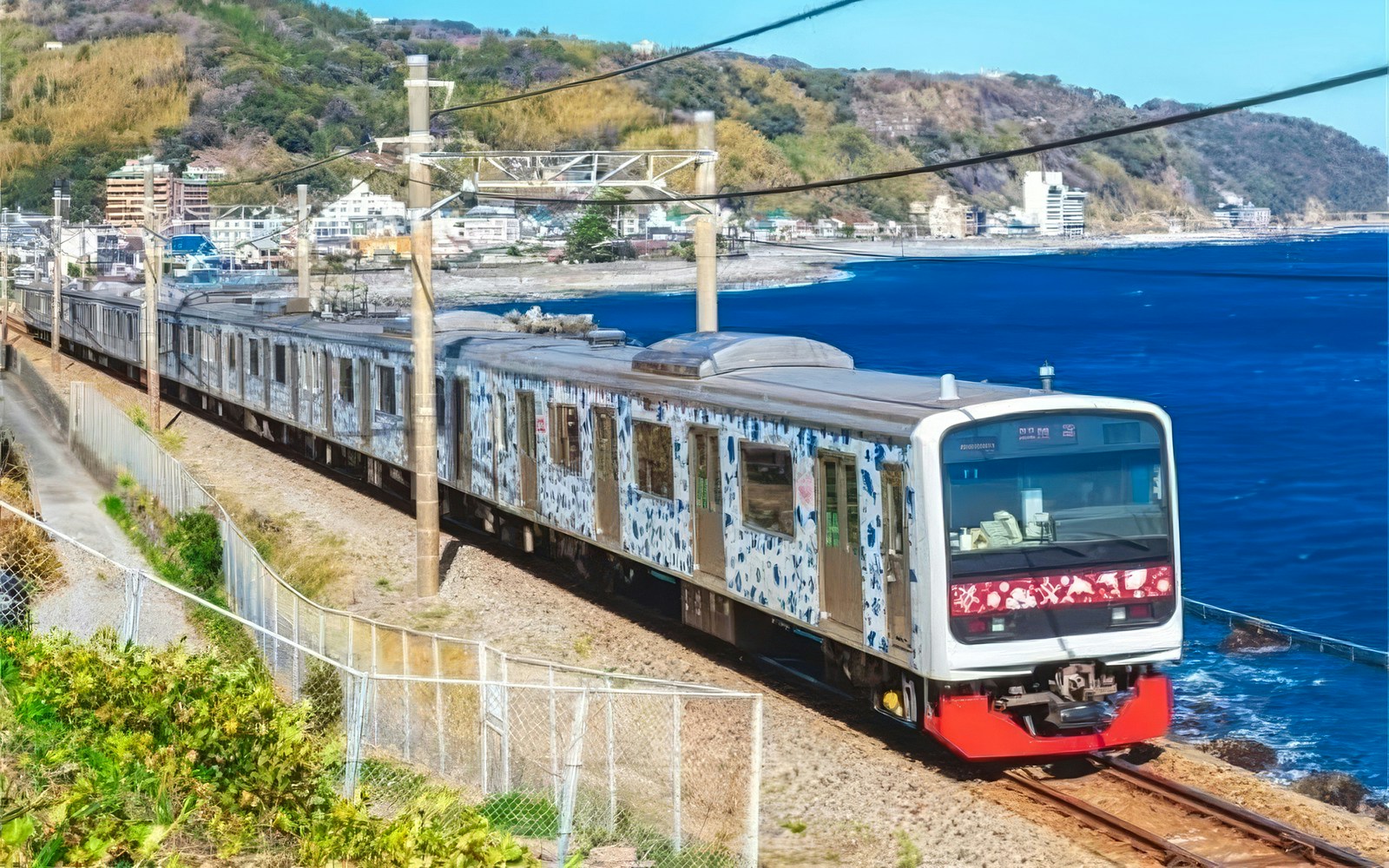 Izukyu 3000 series "Aloha Train" traveling along a coastal railway in Japan.