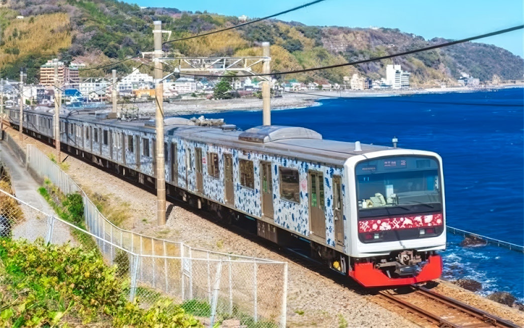 Izukyu 3000 series "Aloha Train" traveling along a coastal railway in Japan.