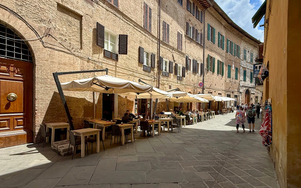 Outdoor seating at a cafe in Siena, Italy, ideal for pasta cooking classes.