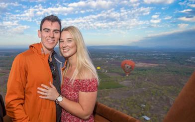 Couple enjoying a hot air balloon ride over Cairns with scenic landscape views.