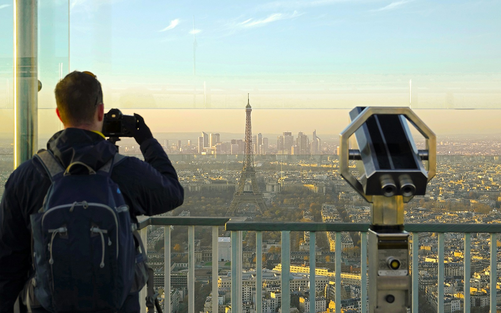 Tourist photographing Eiffel Tower from Montparnasse Tower terrace in Paris.