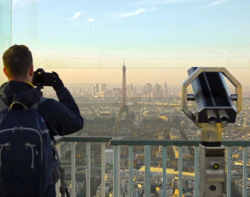 Tourist photographing Eiffel Tower from Montparnasse Tower terrace in Paris.
