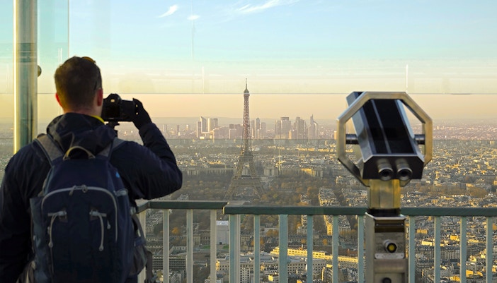 Tourist enjoying panoramic view from Montparnasse Tower terrace, Paris.