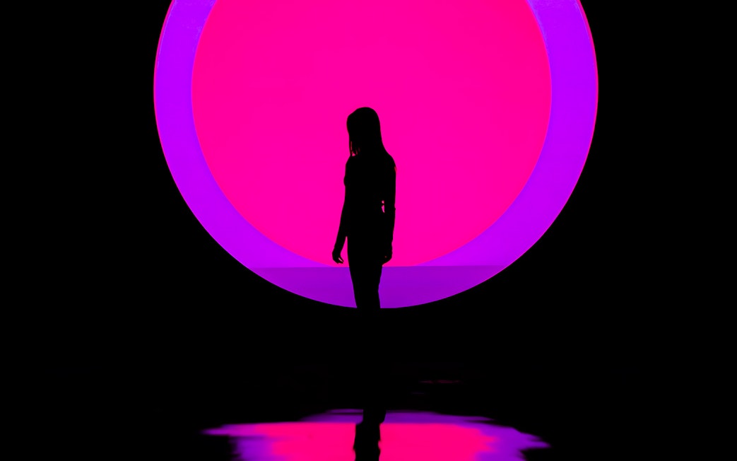 Silhouette of a person in front of a vibrant pink and purple circle at ARTE Museum.