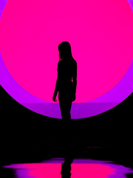 Silhouette of a person in front of a vibrant pink and purple circle at ARTE Museum.