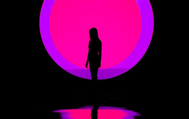 Silhouette of a person in front of a vibrant pink and purple circle at ARTE Museum.