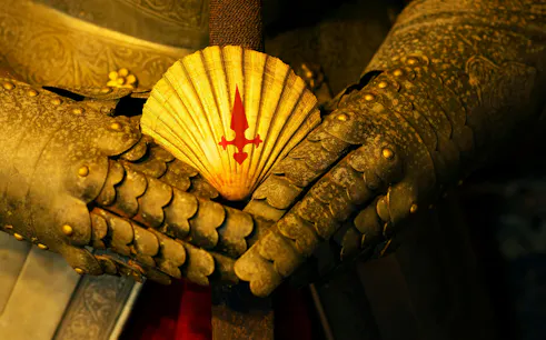Scallop shell with red cross on sword hilt, medieval armor, Camino de Santiago, Spain.