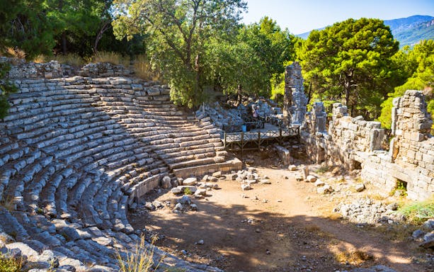 Ancient amphitheater ruins surrounded by trees in Phaselis Bay, Turkey.
