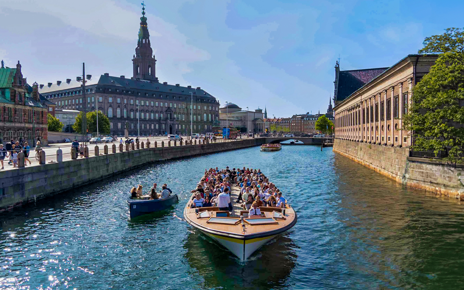 Copenhagen canal tour boat passing colorful Nyhavn waterfront buildings.