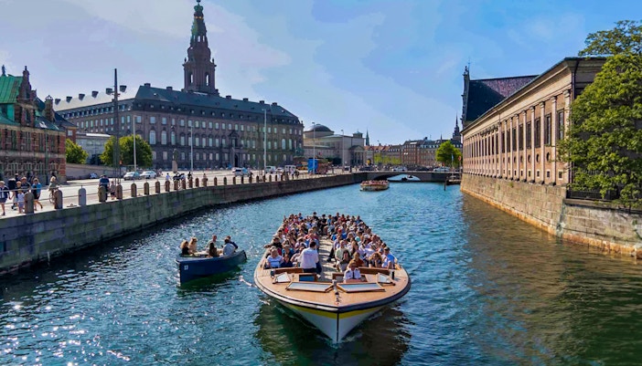 Copenhagen canal tour boat passing colorful Nyhavn waterfront buildings.