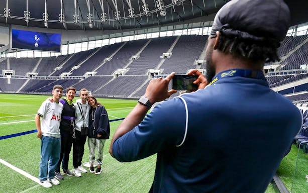 Group posing for a photo on the field at Tottenham Hotspur Stadium during a guided tour.