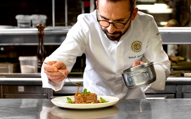 Chef preparing gourmet dish for Paris New Year’s Eve 2025 cruise by Bateaux Parisiens.