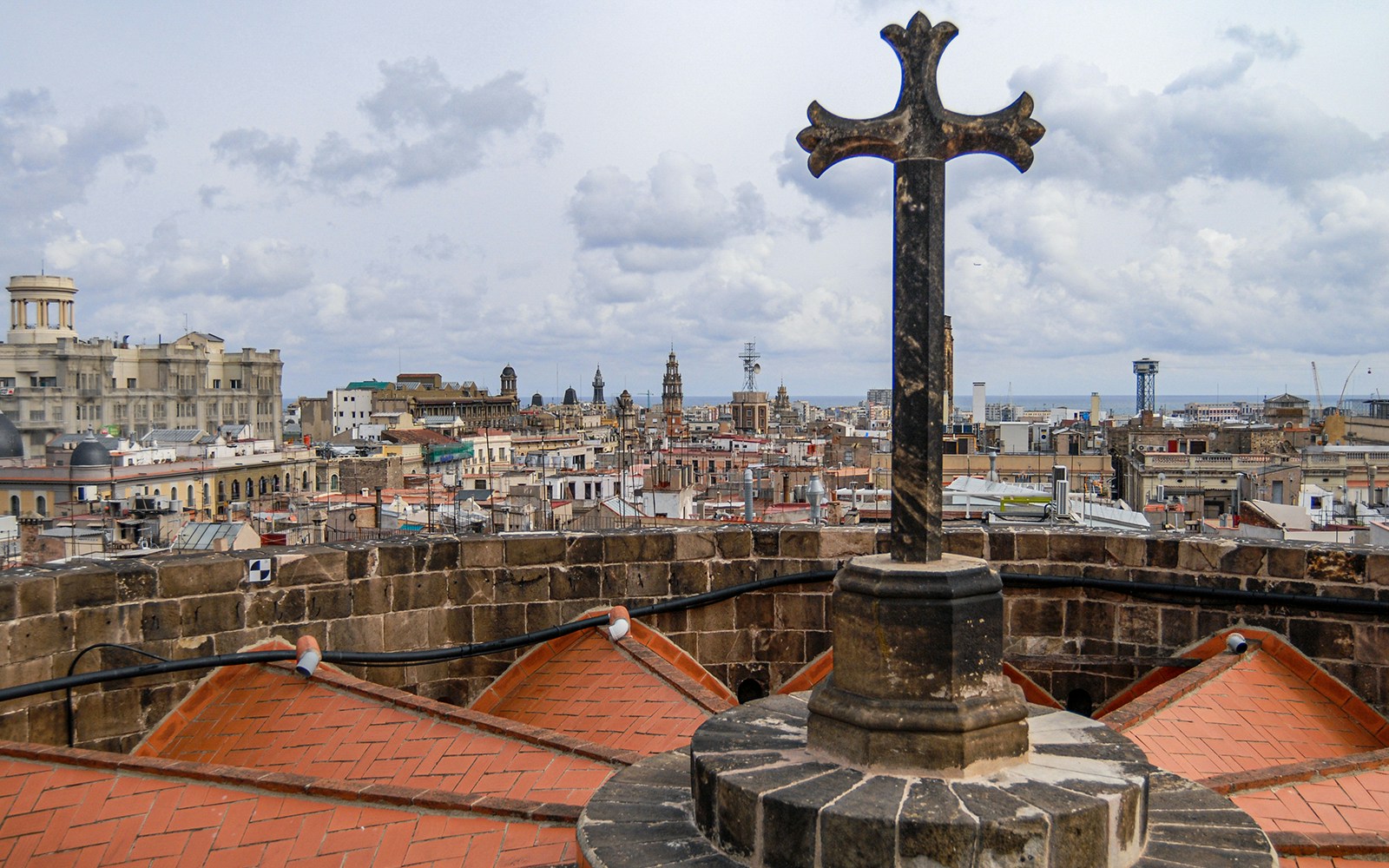 Barcelona Cathedral rooftop view with cross and cityscape.