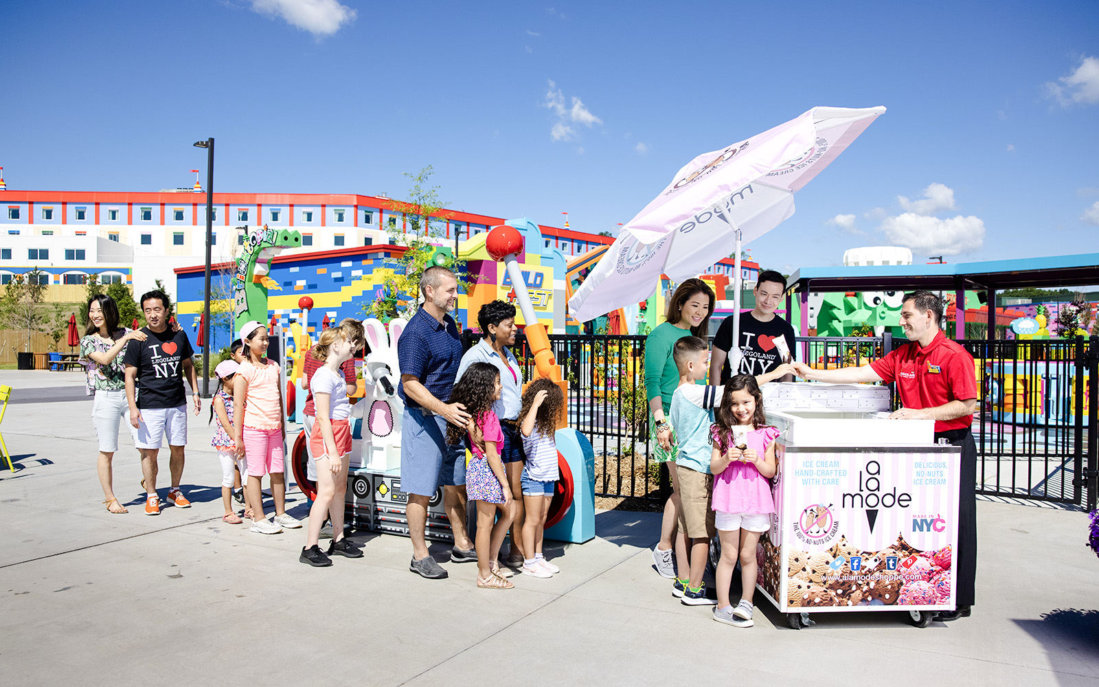 Guests enjoying ice cream at Legoland New York with colorful buildings in the background.