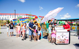 Guests enjoying ice cream at Legoland New York with colorful buildings in the background.