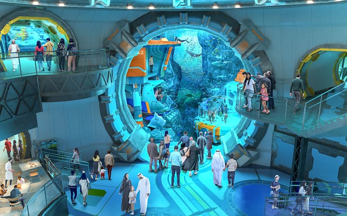 Visitors exploring an underwater-themed attraction with large viewing windows.