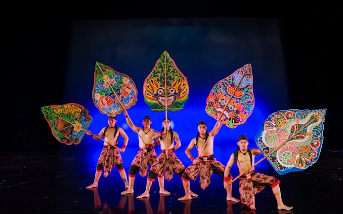 Performers with colorful shields on stage during the Devdan Show in Bali.
