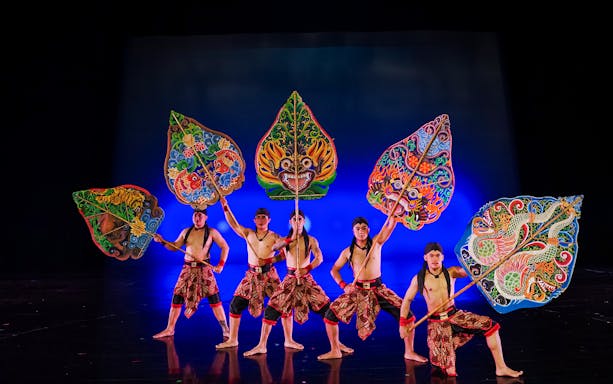 Performers with colorful shields on stage during the Devdan Show in Bali.