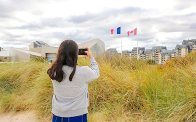 Visitor photographing flags at Juno Beach Centre, Normandy, France.