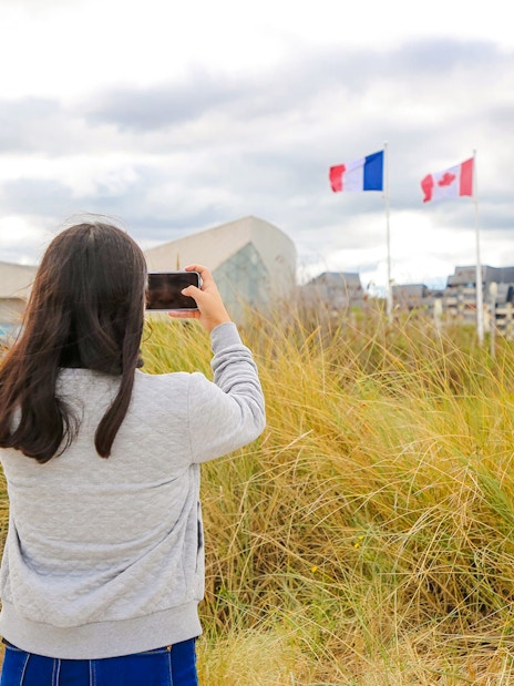 Visitor photographing flags at Juno Beach Centre, Normandy, France.