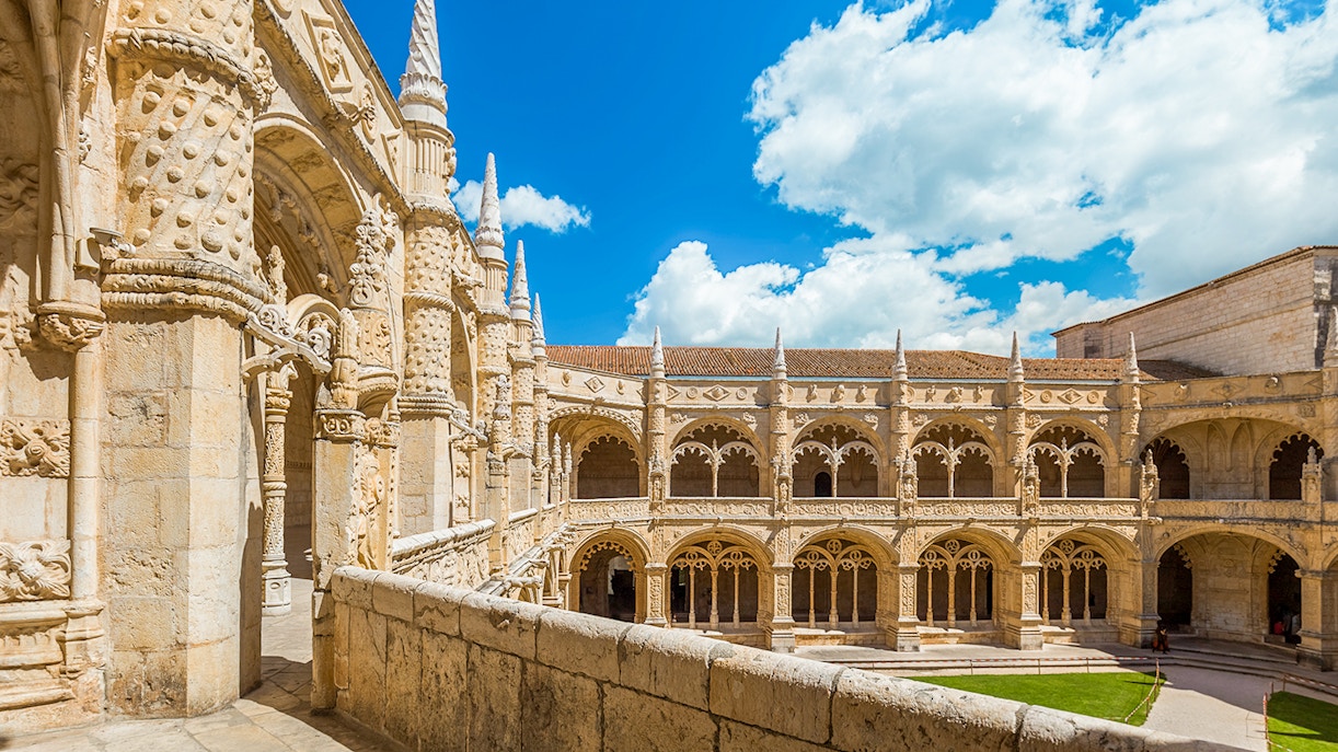 Jeronimos Monastery in Lisbon viewed from a balcony, showcasing its intricate Gothic architecture.