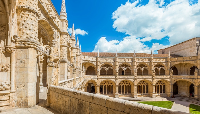 Jeronimos Monastery in Lisbon viewed from a balcony, showcasing its intricate Gothic architecture.