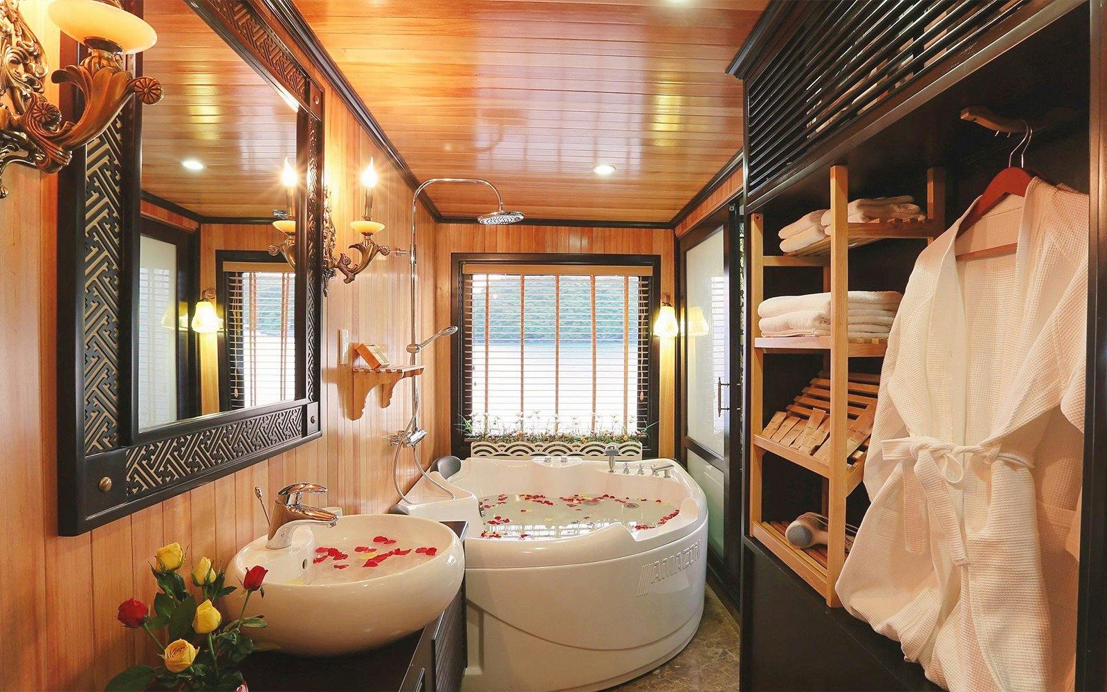 Jacuzzi with rose petals in a luxurious Halong Bay cruise cabin bathroom.