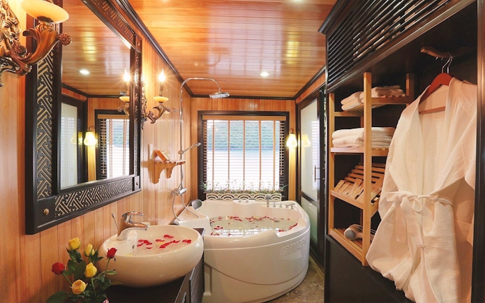 Jacuzzi with rose petals in a luxurious Halong Bay cruise cabin bathroom.