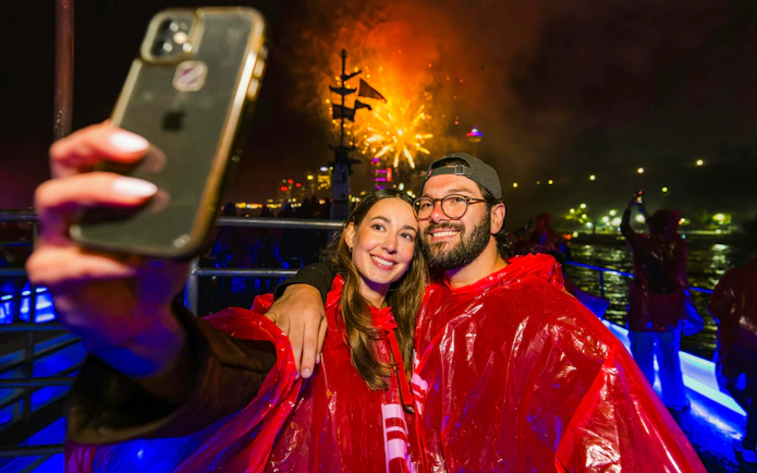 Couple taking selfie on Niagara Falls fireworks boat cruise at night.
