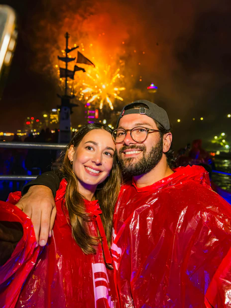 Couple taking selfie on Niagara Falls fireworks boat cruise at night.